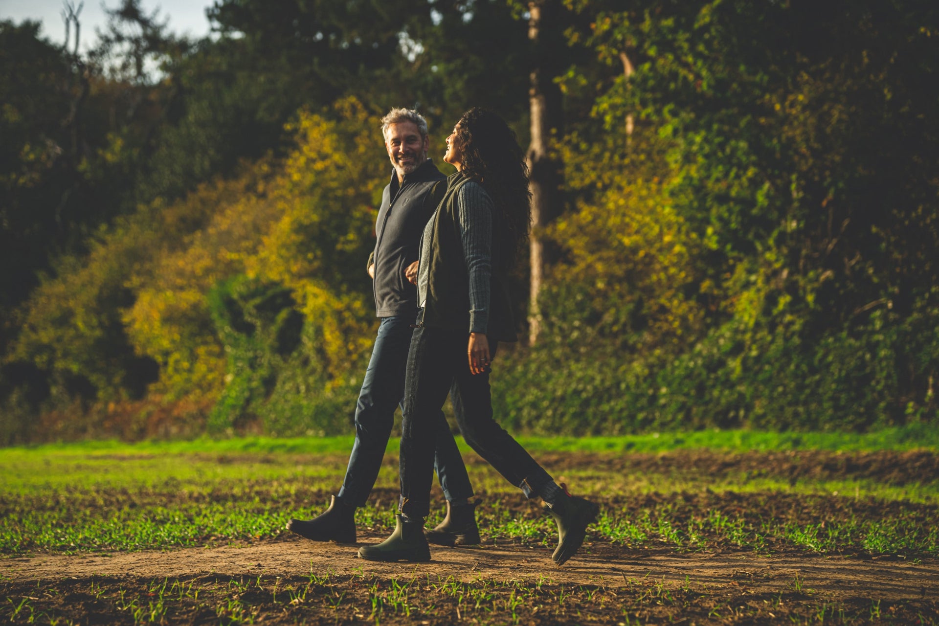 Man and woman walking outdoors in boots and fleece layers