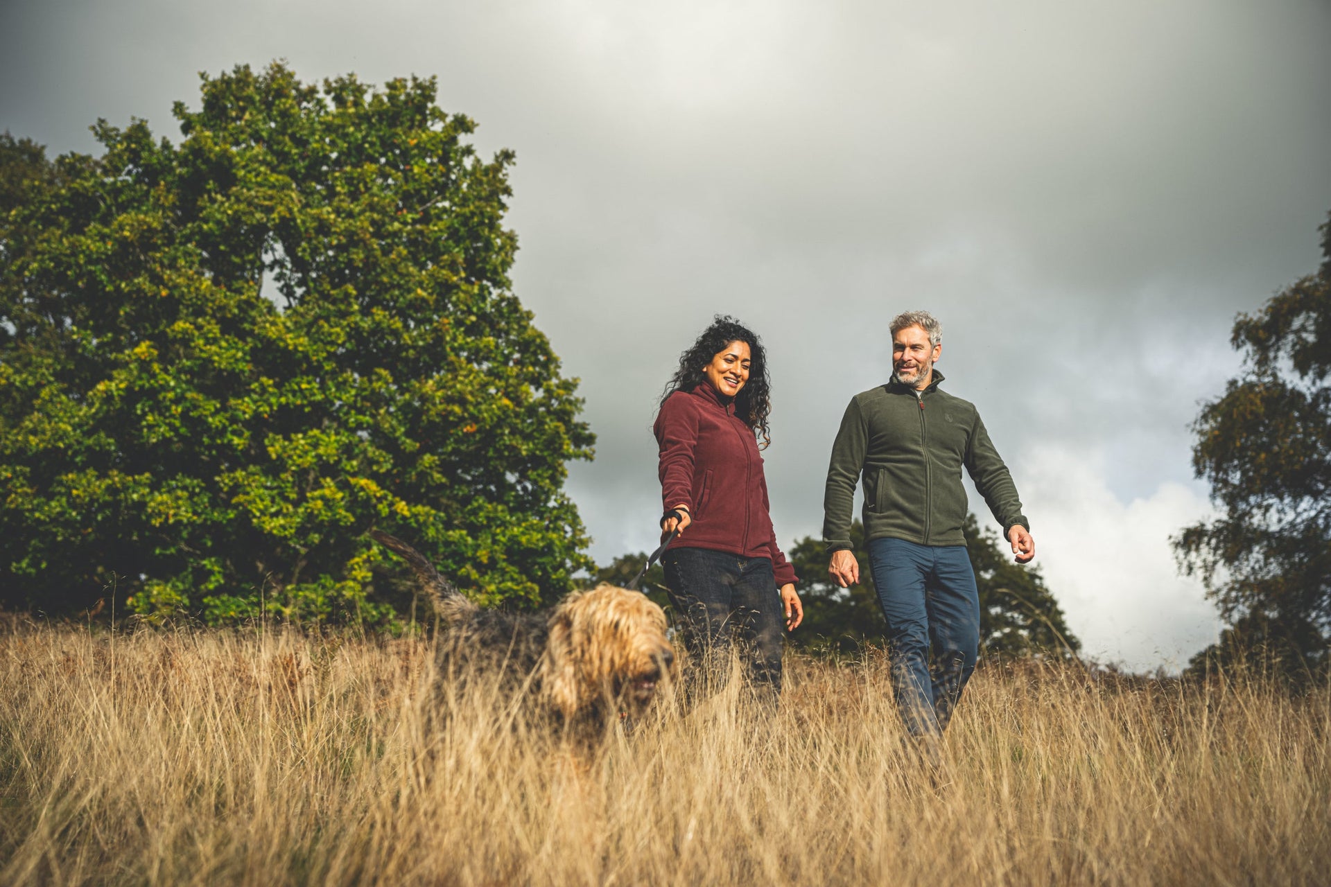 Man and woman walking dog in fleece jackets