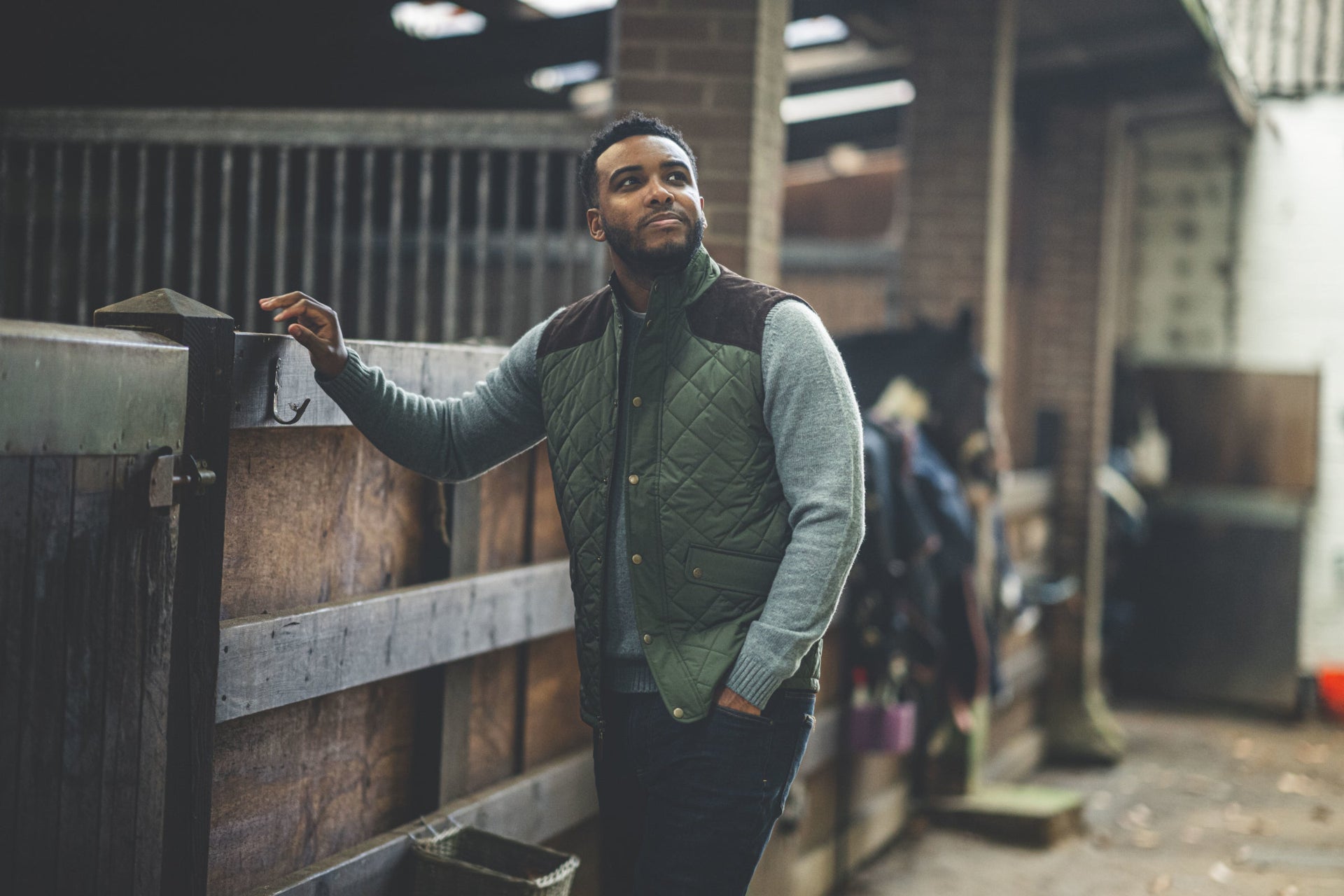 Man in a green quilted gilet standing in a stable