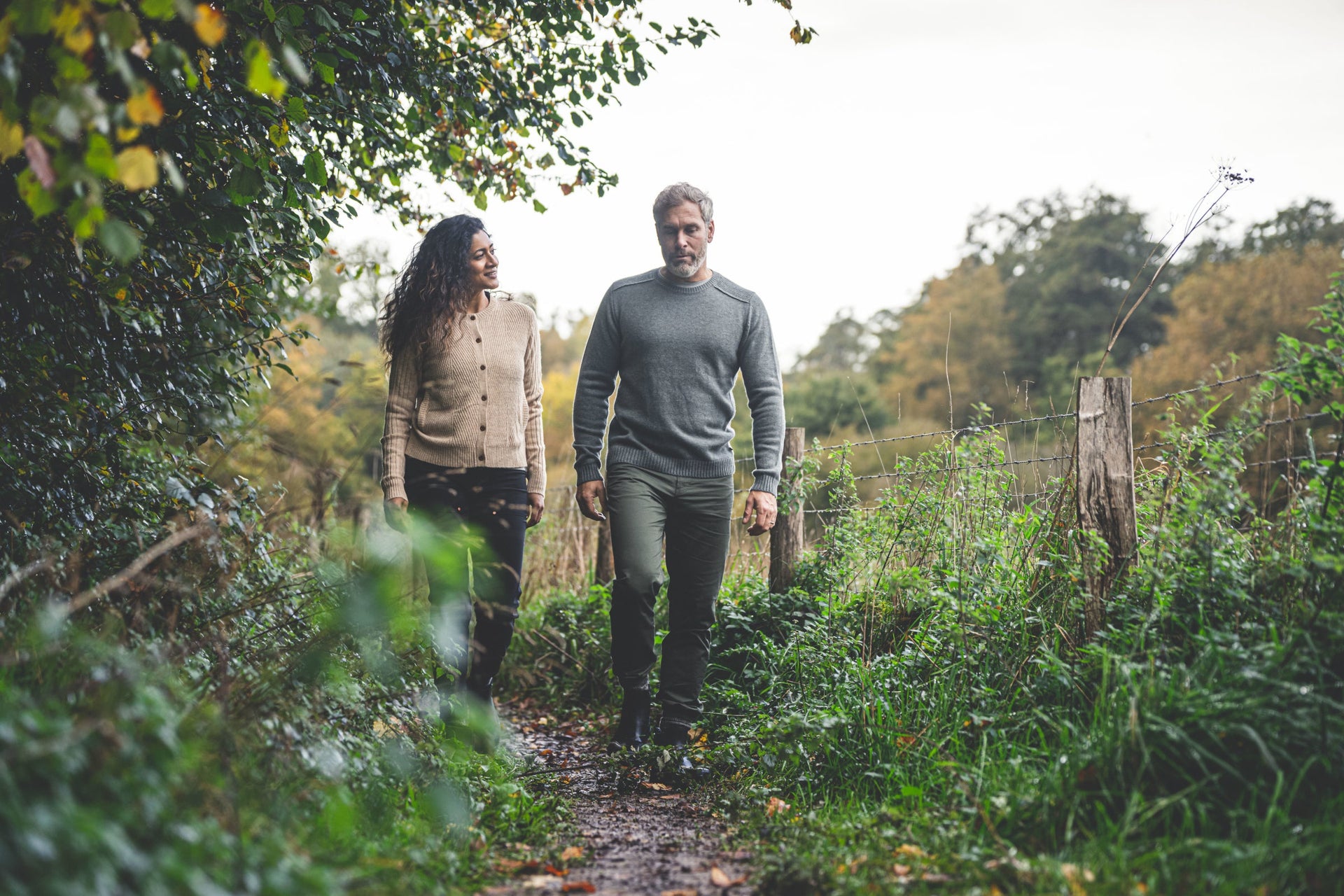 Man and woman walking on a woodland path in knitwear