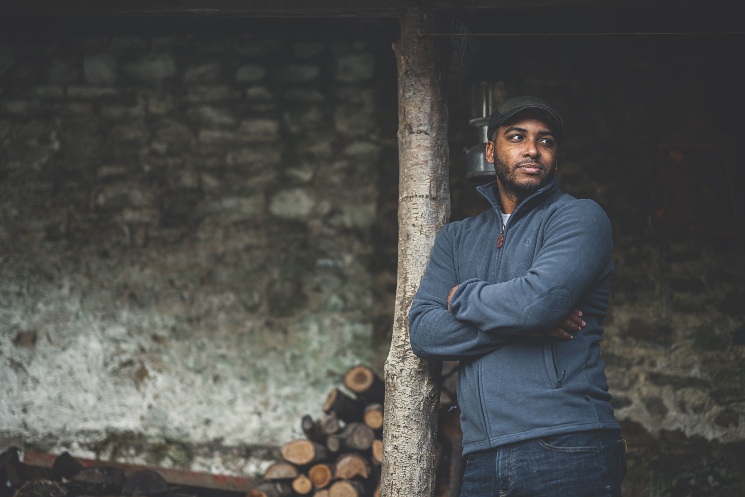 A man leaning against a tree, wearing a Wilde & King fleece